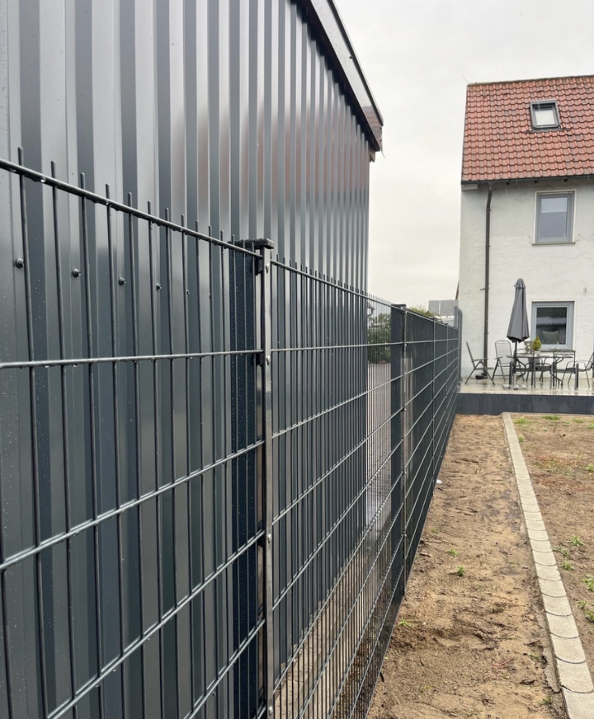 Doppelstabmattenzaun entlang eines Gebäudes mit Blick auf den weiteren Verlauf